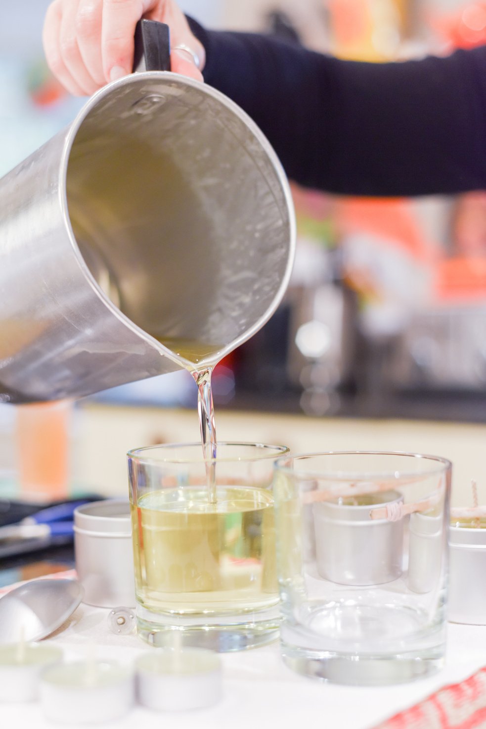 Creative occupation of candle making showing the pouring of liquid wax into jars